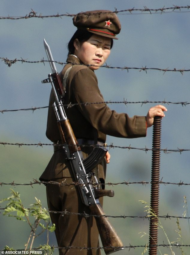 A North Korean soldier looks out from behind barbed wire at a camp