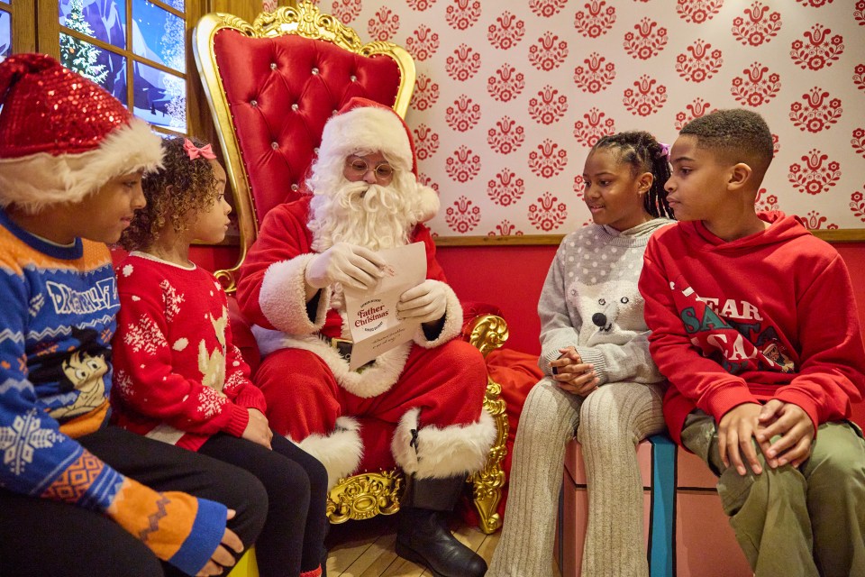 Santa Claus reading a letter with three children.