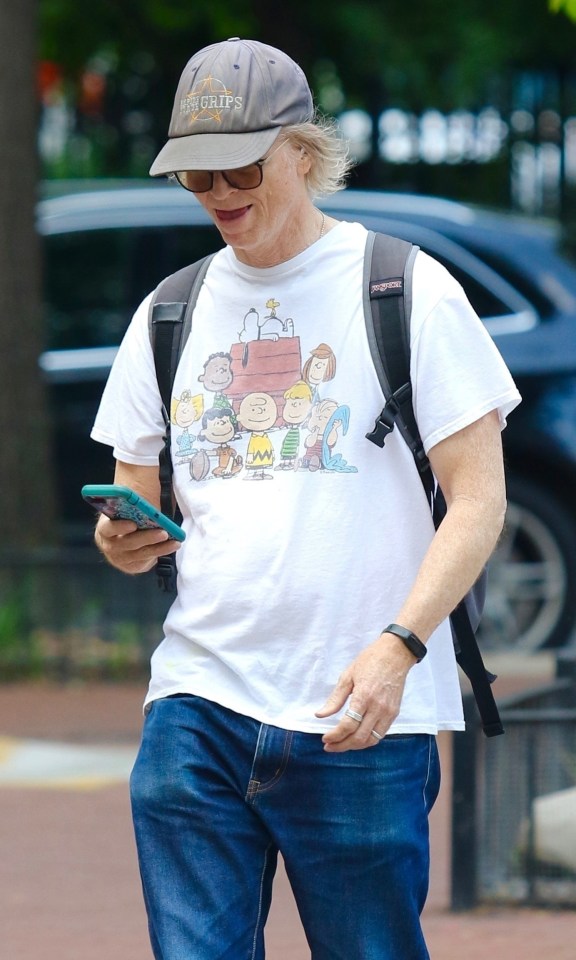 Eric Stoltz walking down the street, looking at his phone.