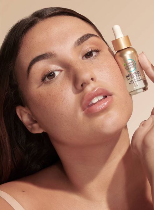 Model holding Garnier Natural Bronzer self-tan face drops.