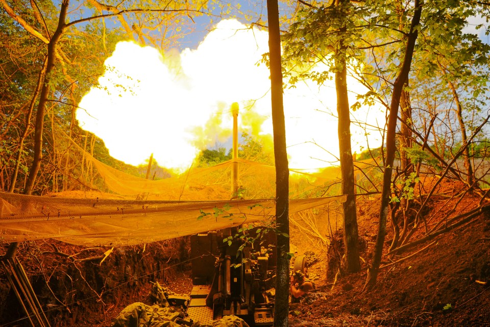 Ukrainian servicemen firing a howitzer.