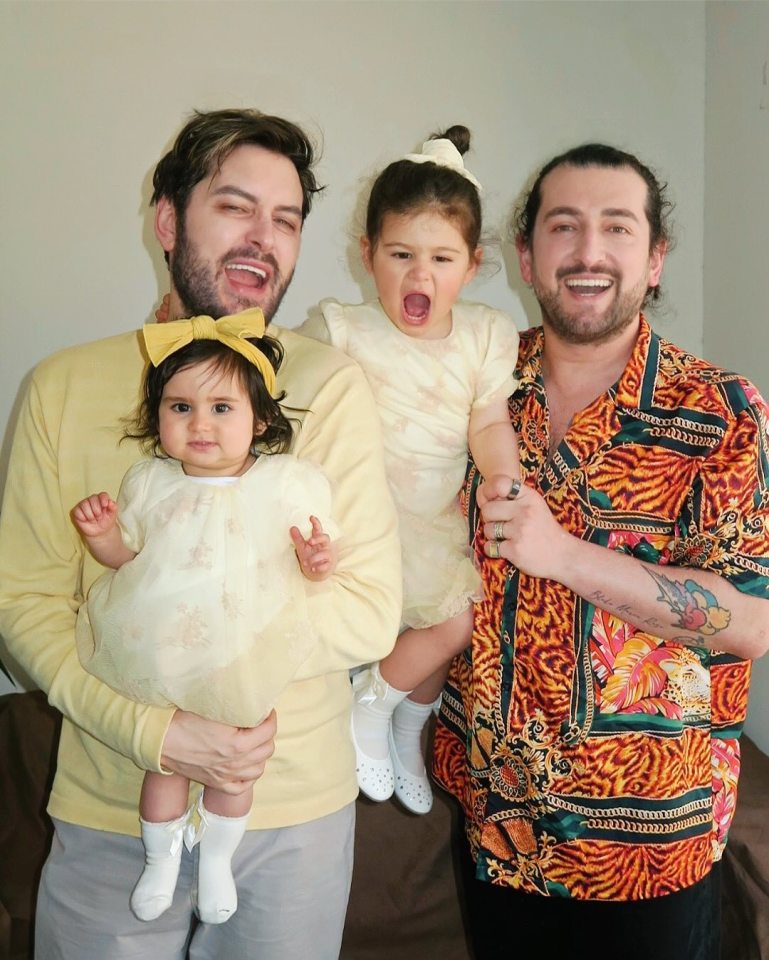 Family Easter photo: two dads holding their two young daughters.