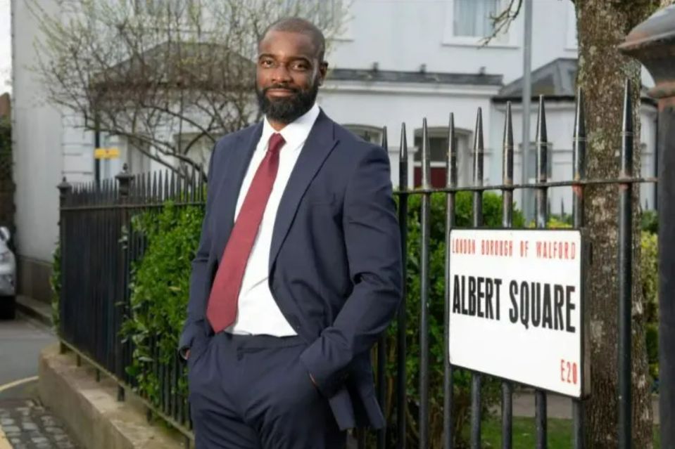 Man in suit standing by Albert Square street sign.