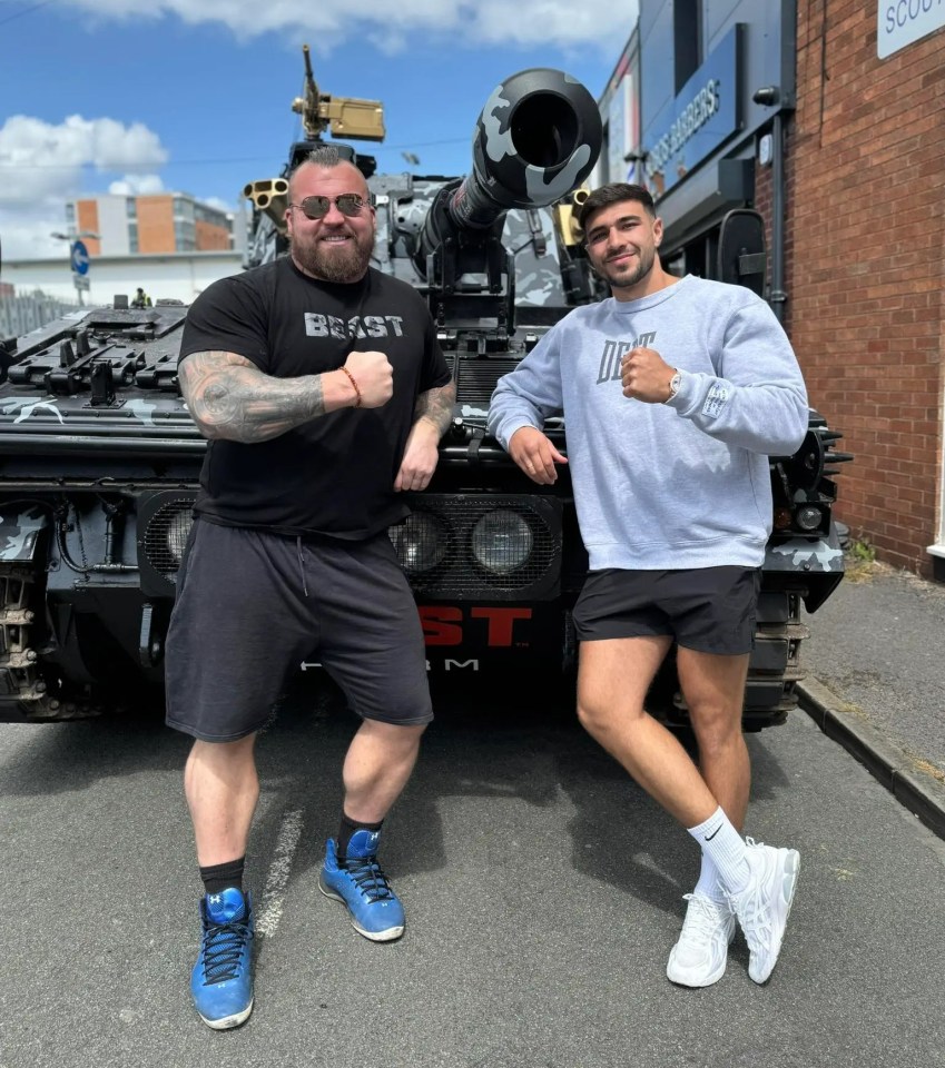 Eddie Hall and Tommy Fury standing by a tank.