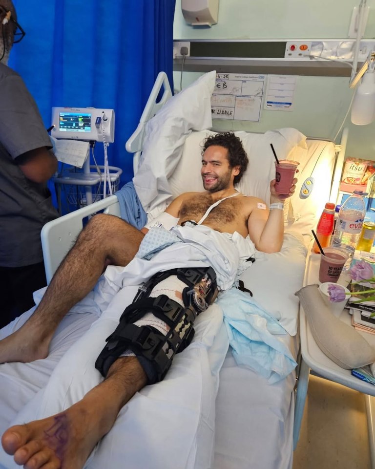 Man in hospital bed with leg brace, drinking a smoothie.