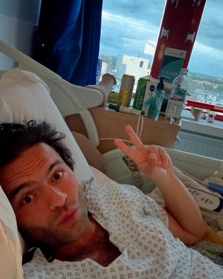 Man in hospital bed giving peace sign.