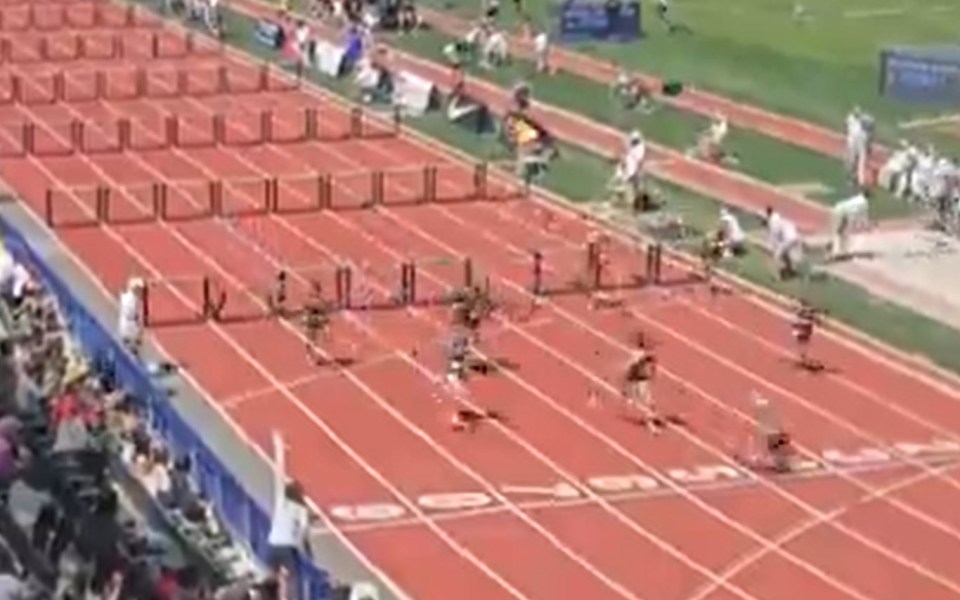 A runner trips at the finish line of a hurdle race but wins despite the fall.