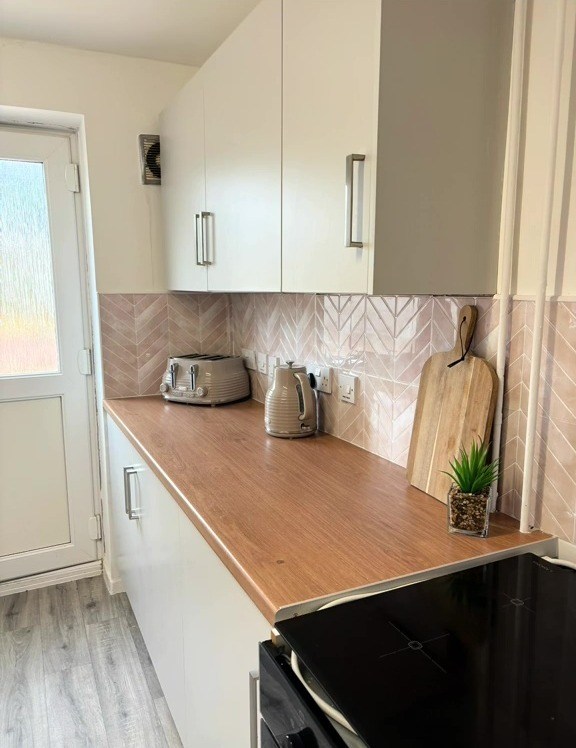 DIY kitchen makeover with pink chevron tile backsplash and wood countertop.