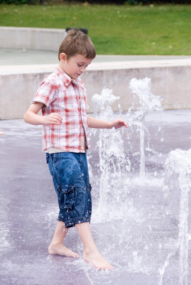 Boy playing in a park fountain.