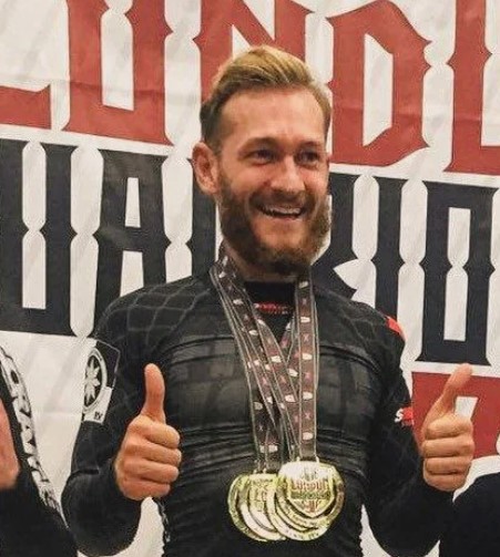 Man giving thumbs up, wearing medals.
