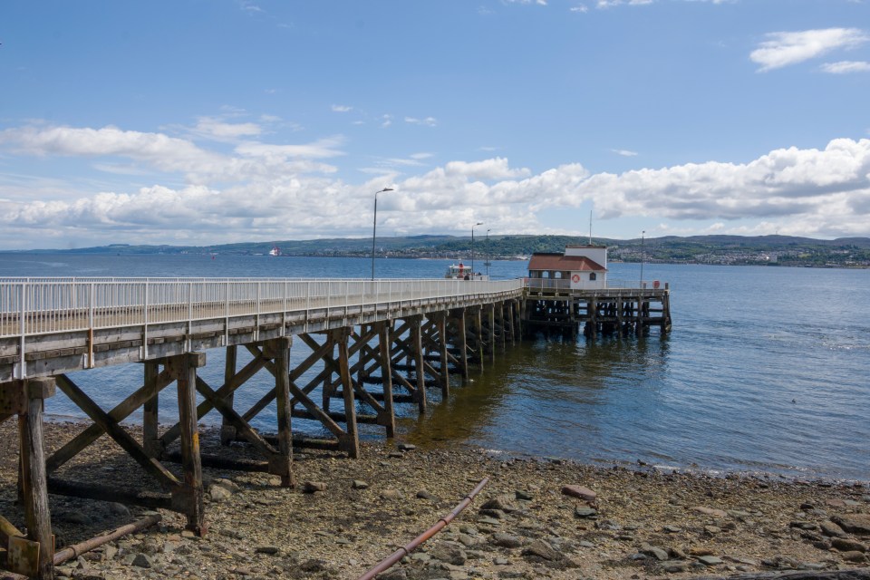 Pier extending over the water toward a small building.