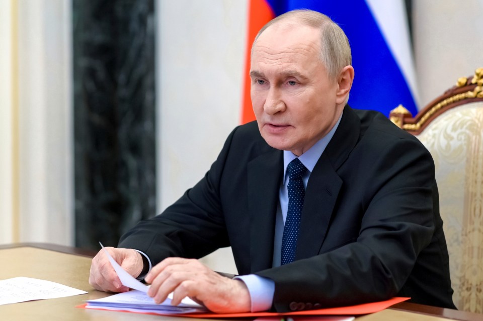Vladimir Putin reviewing documents at a meeting.