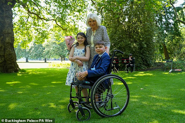 Queen Camilla with Tony Hudgell and Lyla O'Donovan from Catterick, during a private tea party in the gardens at Buckingham Palace -- June 2024