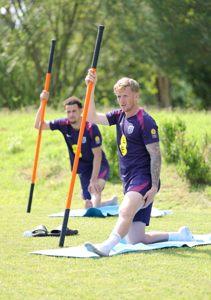 Jordan Pickford and an England teammate stretching during practice.