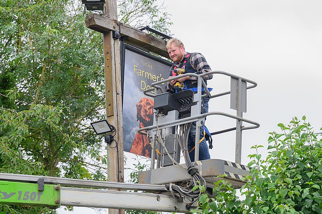 In one snap Kaleb Cooper has a big smile on his face as he puts The Farmer's Dog sign up outside the boozer