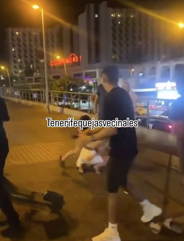 At the start of the clip one of the women appears to tackle the other, sending her crashing onto the tarmac