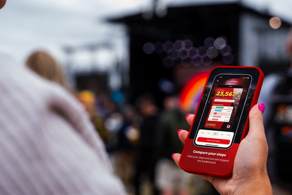 Person holding phone displaying Glastonbury Festival app step count.