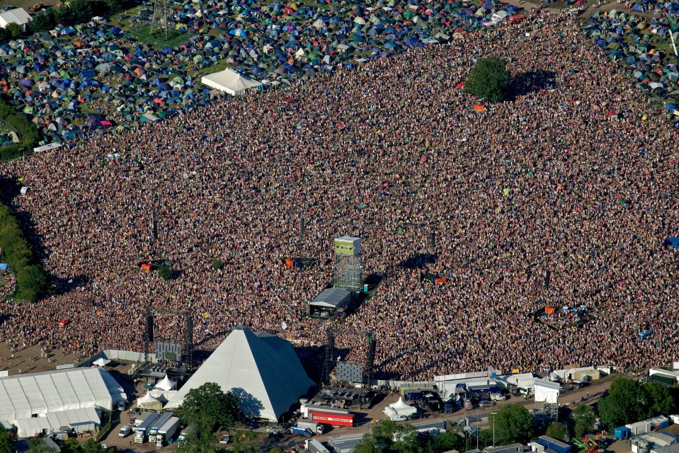 Aerial view of Glastonbury Festival's Pyramid Stage and massive crowd.