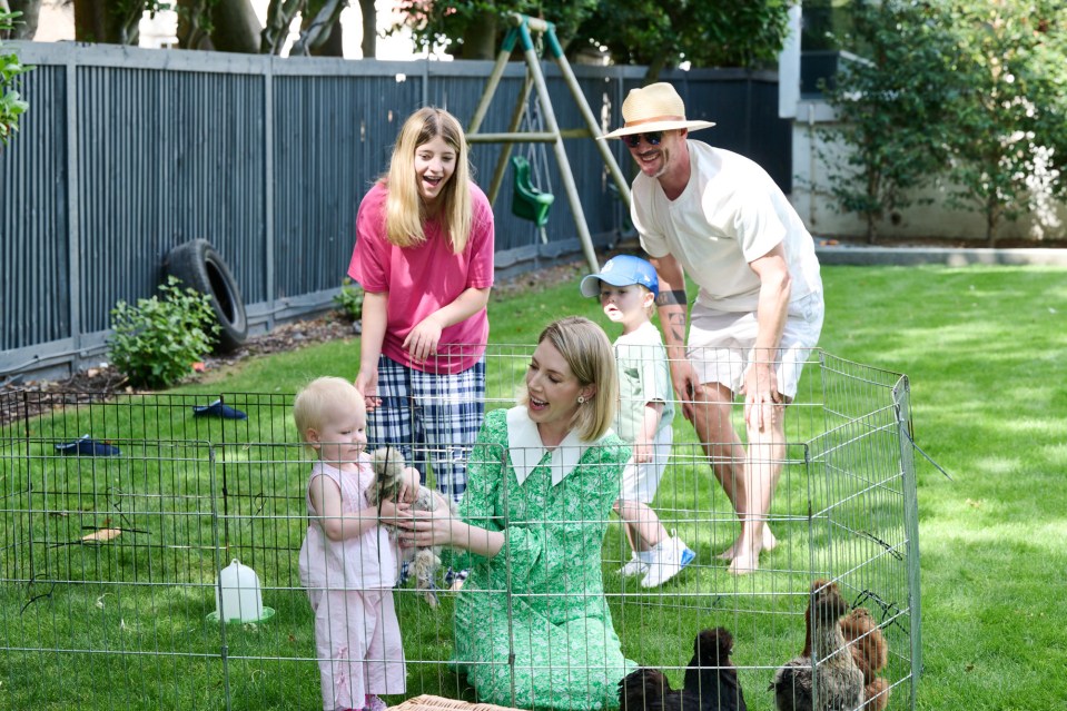 Family with young children looking at chickens in a pen in their backyard.