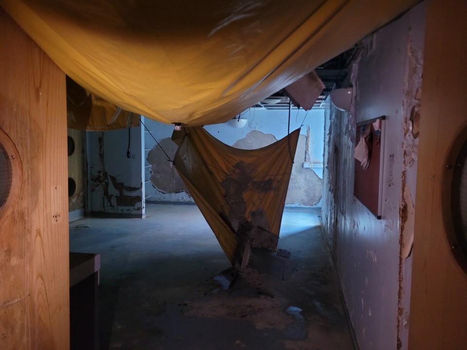 Damaged ceiling and walls in an abandoned hospital corridor.