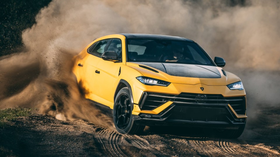 Yellow Lamborghini Urus driving on a dirt road.