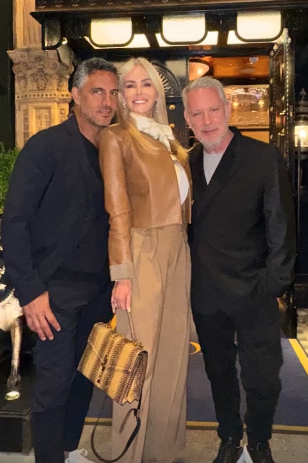 Photo of three people posing together outside a building.