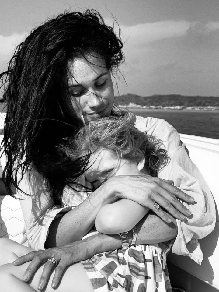 Black and white photo of a woman hugging a child on a boat.