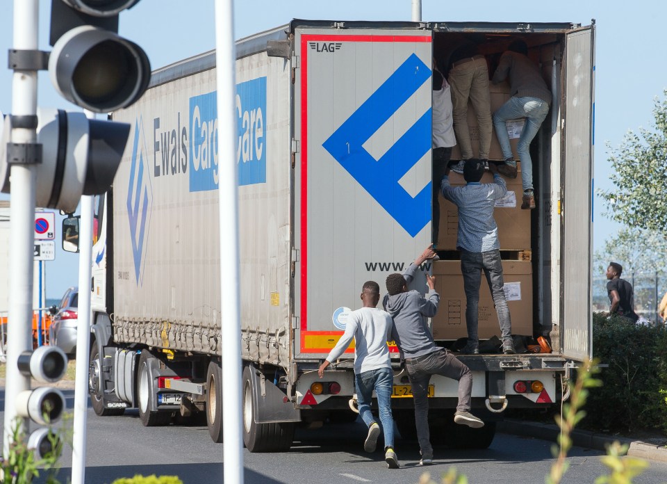 Migrants climbing into the back of a lorry.