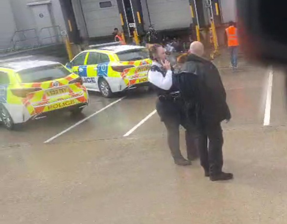 Police officers detaining a person at a distribution center.