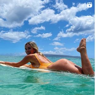 Kayla Simmons in a photoshoot, wearing a black crop top and bikini bottoms.