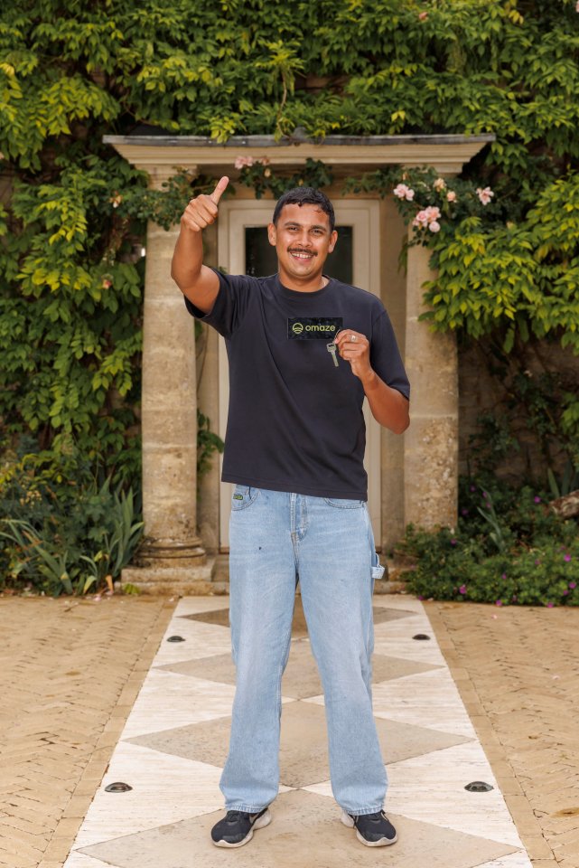 A man gives a thumbs-up while holding keys to his new £5 million home, won via an Omaze draw.