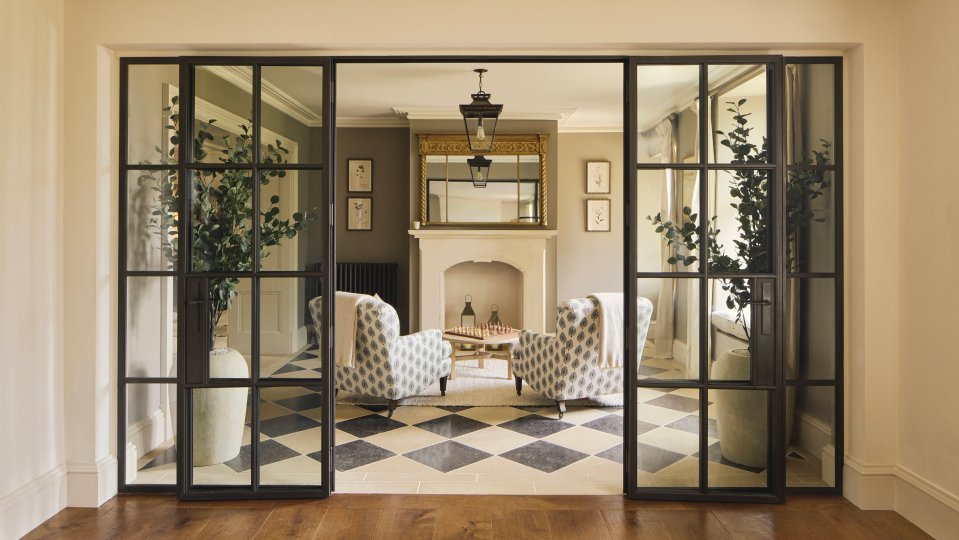 Interior view of a Cotswolds home's sitting room, seen through glass doors.