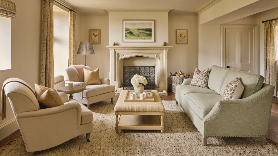 Interior of a Cotswolds home with a fireplace, sofas, and armchairs.