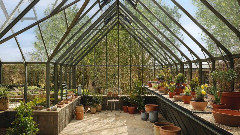 Interior of a glass greenhouse with potted plants.