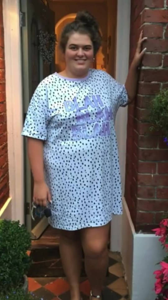 Woman in a polka dot dress standing by a doorway.