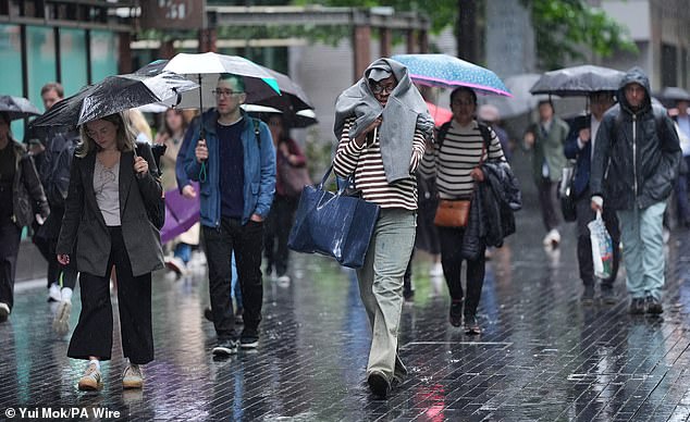 People make their way through the rain in the Southwark area of London yesterday