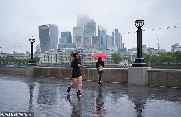 People run or walk through the rain on The Queen's Walk on London's South Bank yesterday