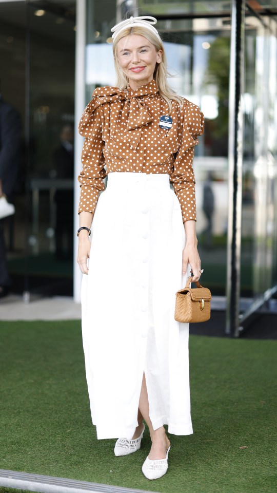 Woman in polka dot shirt and white skirt at a horse race.