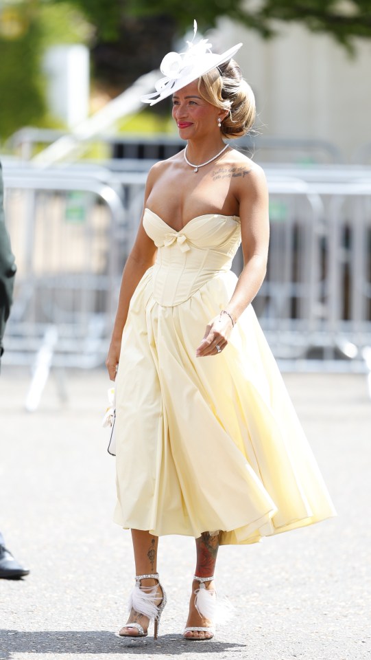Woman in a pale yellow dress and hat at a horse race.