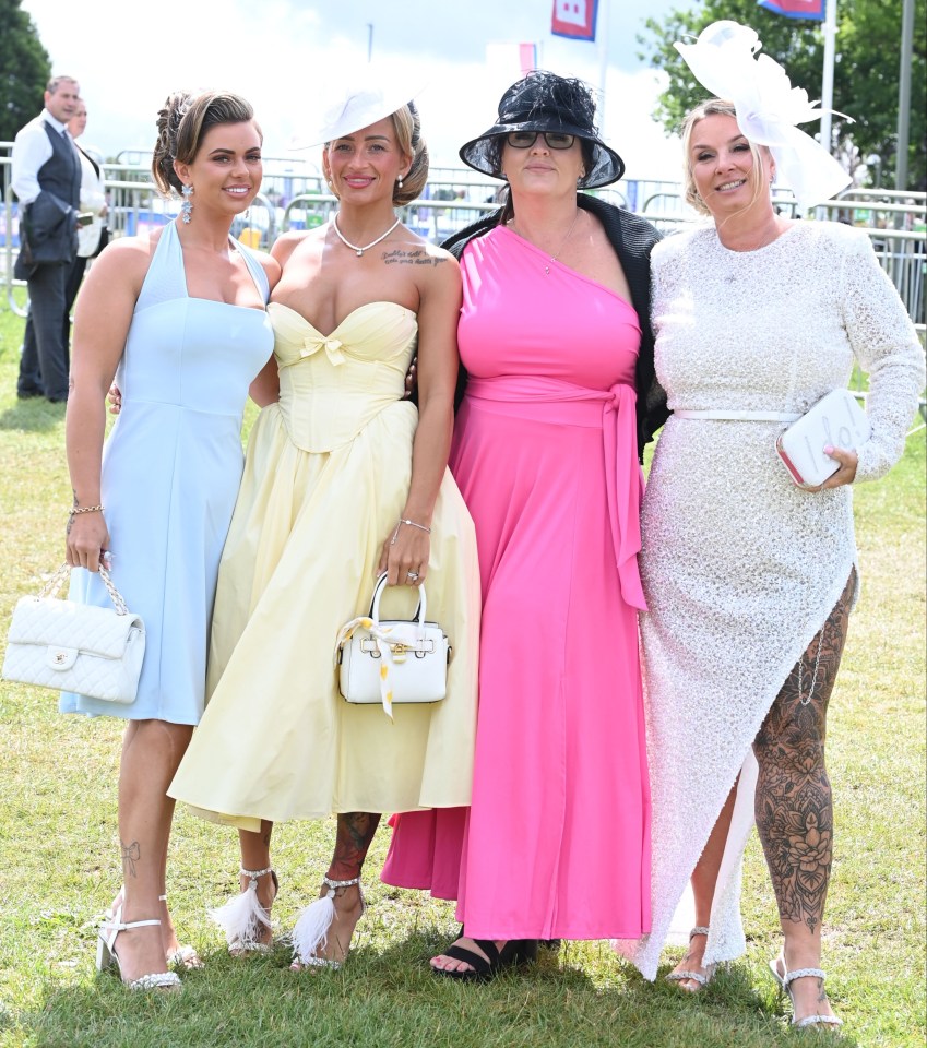 Four women in elegant dresses and hats at the Epsom Derby Festival.