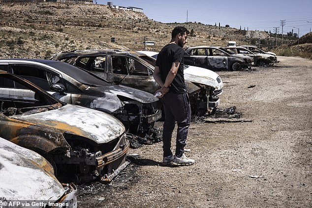 A man looks on at burned vehicles in the Barkan Industrial area, near Salfit in the occupied West Bank, on May 16, 2025, after more than 17 Palestinian workers' cars were reportedly set on fire by Israeli settlers the night before