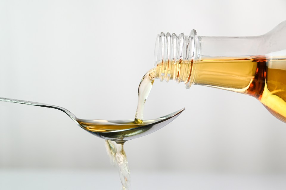 Apple cider vinegar pouring into a spoon.