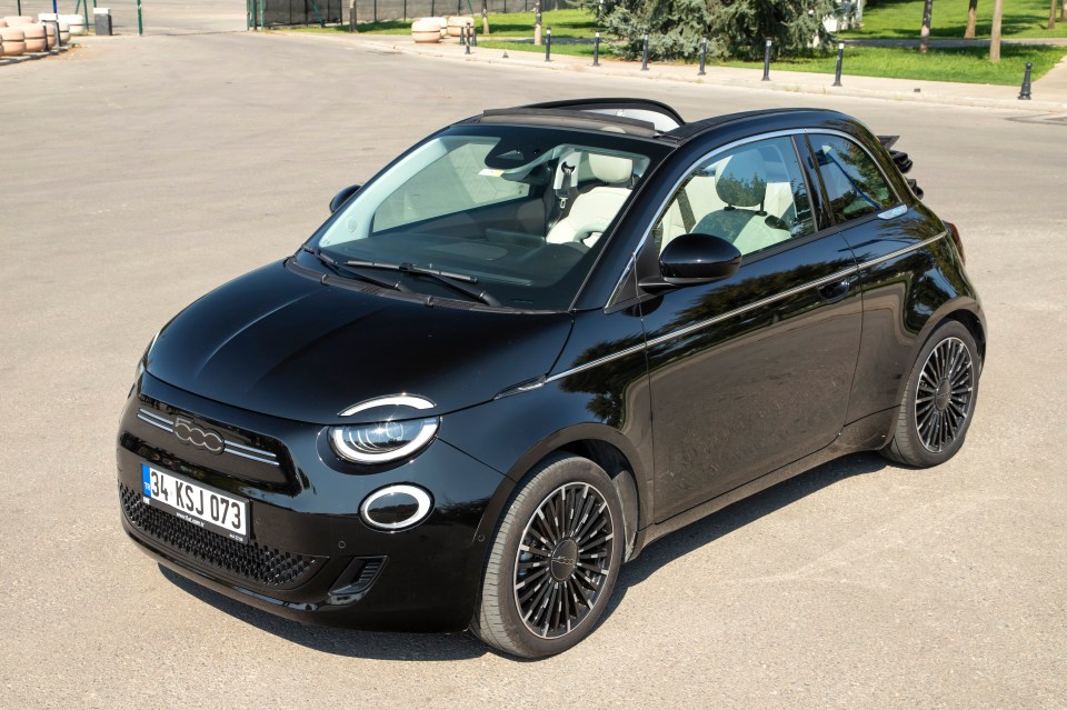 Black Fiat 500e Cabrio parked in a parking lot.