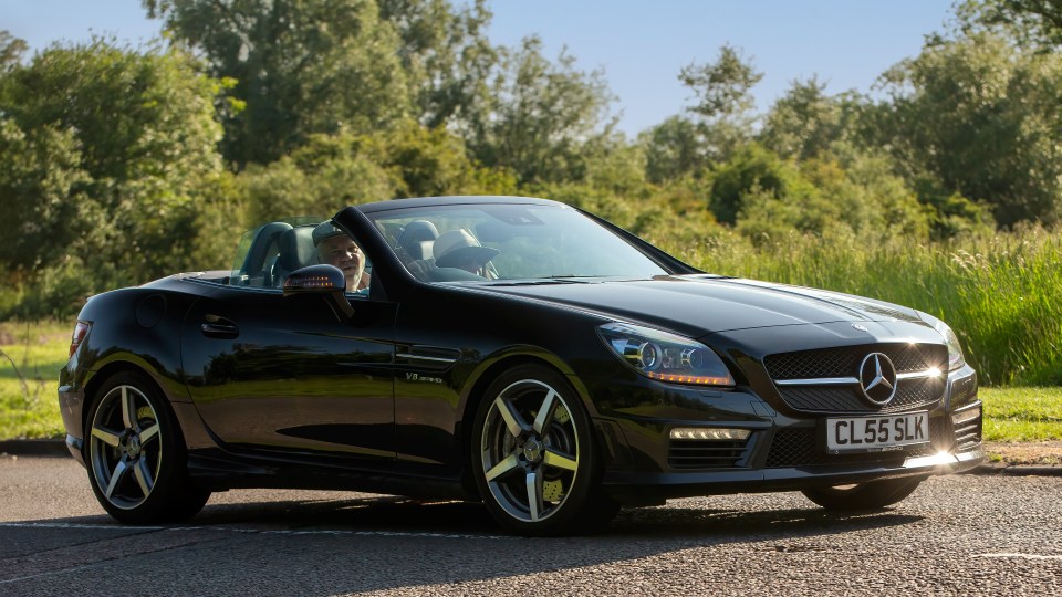 Black Mercedes-Benz SLK driving down a road.