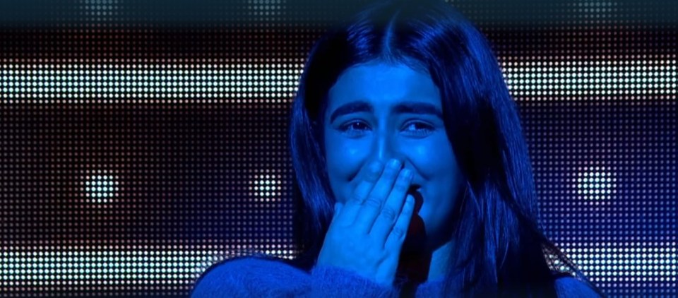 A woman laughing and covering her mouth.