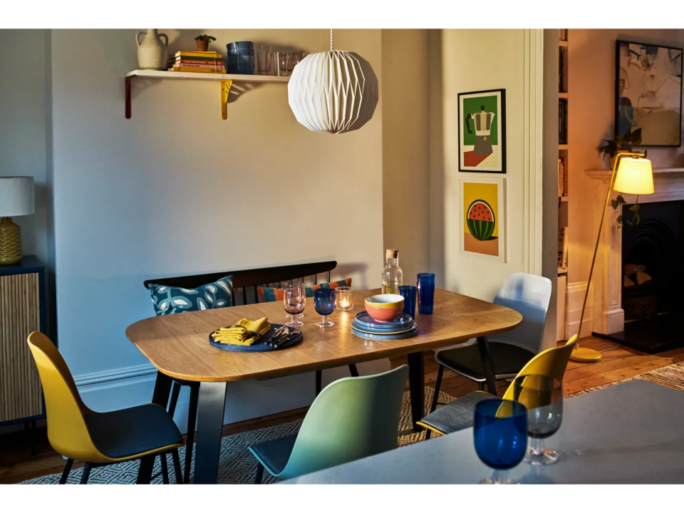 Dining room with wooden table and colorful chairs.