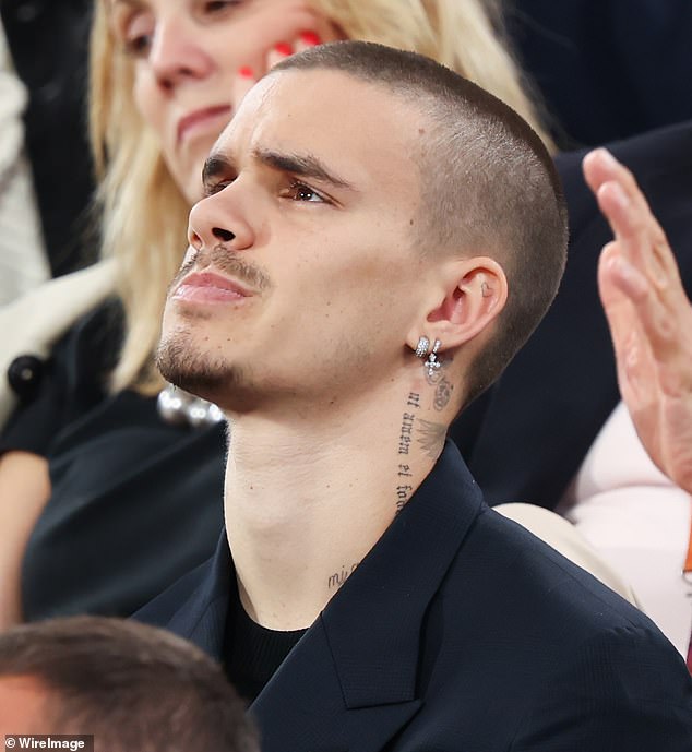 The son of David and Victoria Beckham looked sharp in a dark suit as he pulled faces during the nail-biting game