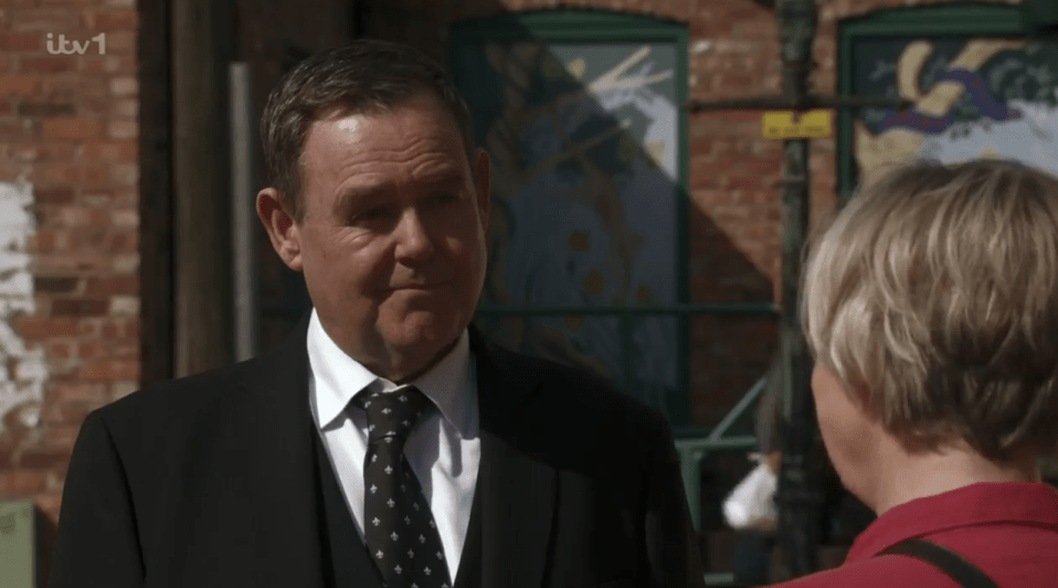 Man in suit speaking to a woman.