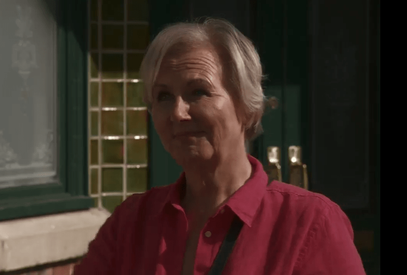 A woman in a red shirt smiles.