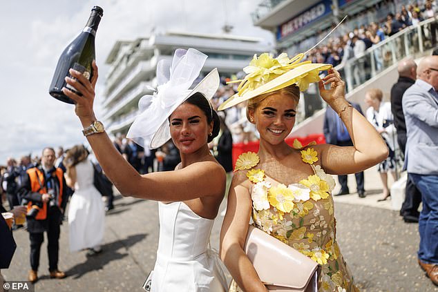 Race-goers pose for a picture as they arrive to watch horse racing during Ladies Day at the Epsom Derby in Epsom Downs in Surrey